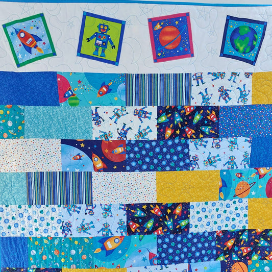 Children's quilt with space-themed fabric squares featuring rockets, robots, and planets.