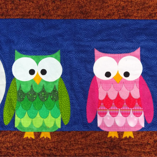 a pink owl and a green owl sitting on a brown branch