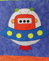 an outer space quilt with a large alien spacecraft on a blue fabric background