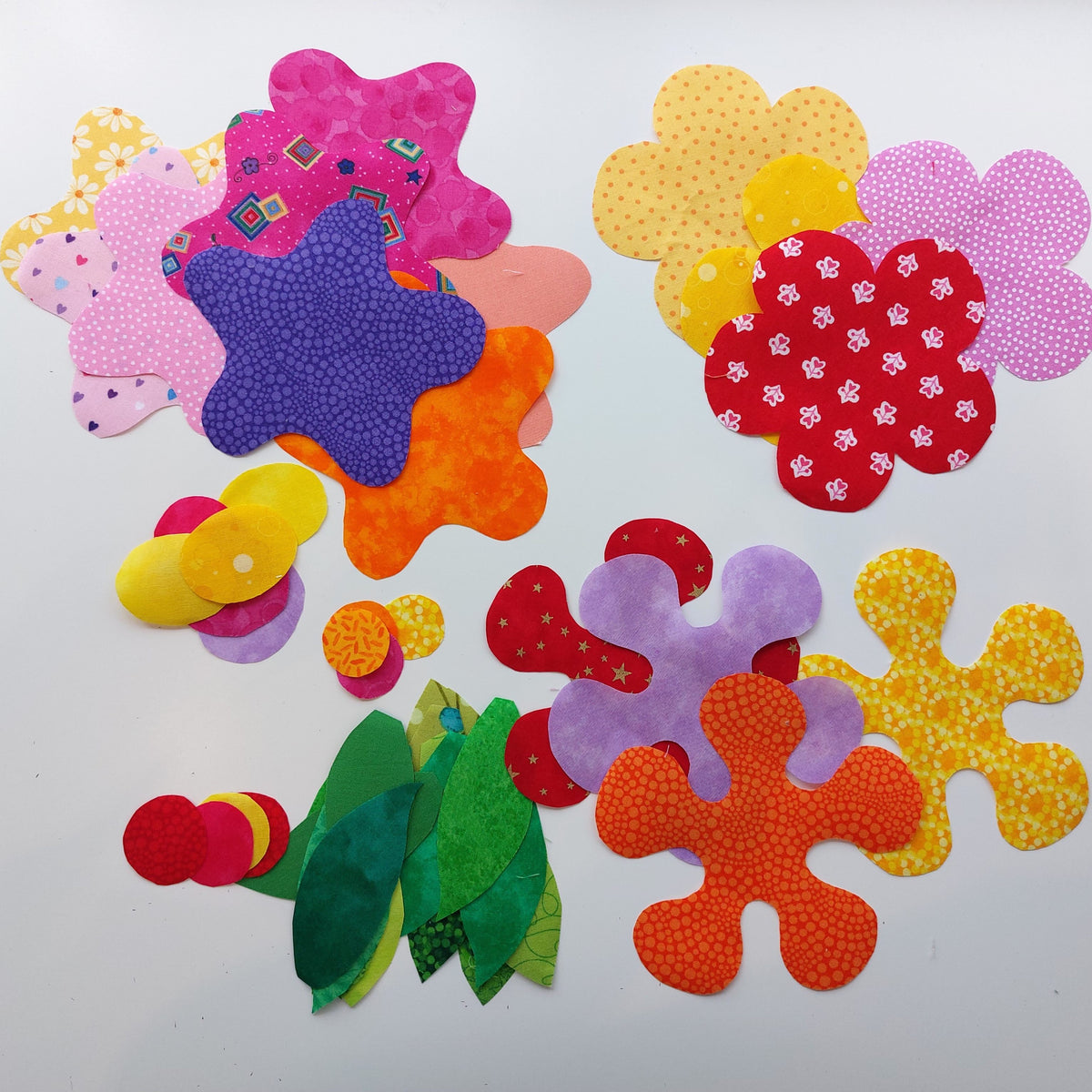 the cut out brightly coloured flowers and leaves ready to be added to the flowers quilt