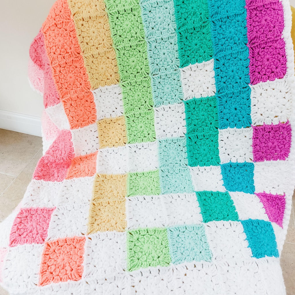 rainbow baby blanket on a chair showing the different coloured flower squares