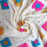 Close-up of a crocheted blanket with colorful flower patterns.