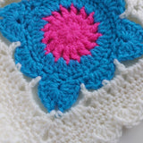 close-up of a crochet blue flower with a pink centre