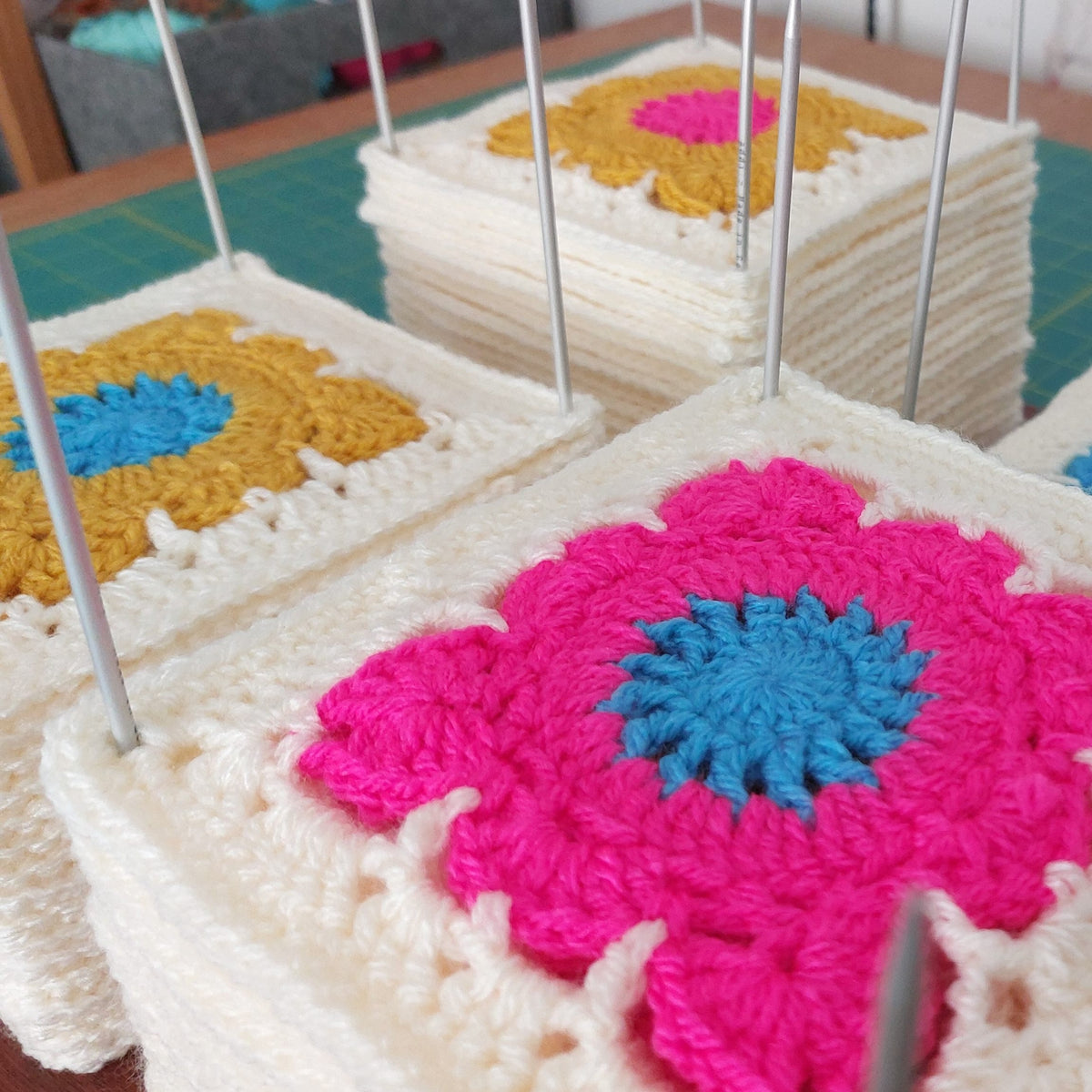 Crocheted squares with floral patterns on a table.