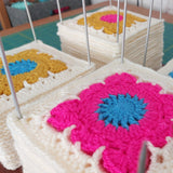 Crocheted squares with floral patterns on a table.