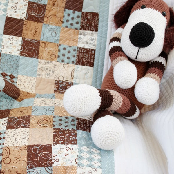 brown, blue and tan patchwork quilt on a chair with a brown and white stuffed toy dog