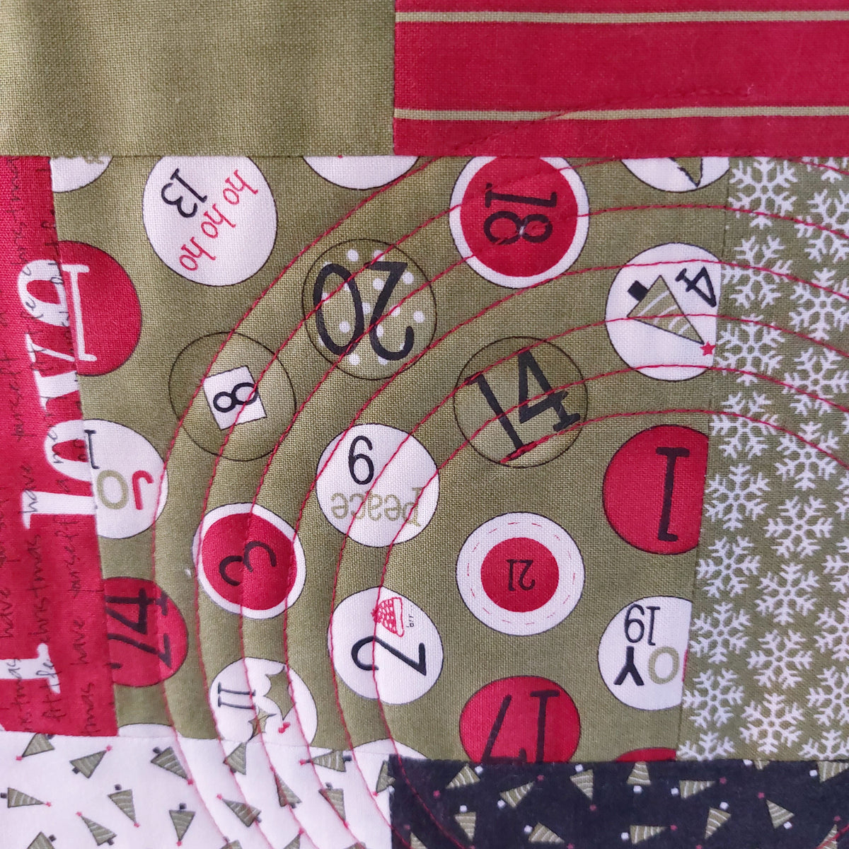 Close-up of a quilt with various patterns including numbers, letters, and snowflakes.