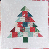 Quilt with a Christmas tree design made of patchwork squares on a white background.