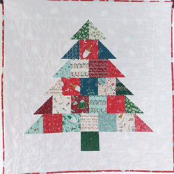 Quilt with a Christmas tree design made of patchwork squares on a white background.