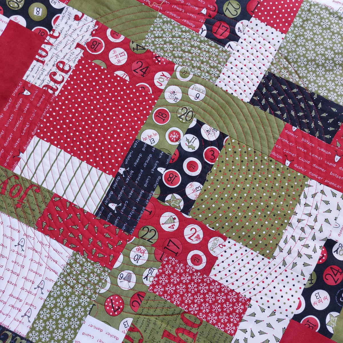 Christmas quilt with patches in green, red, black and white showing numbers counting down to Christmas