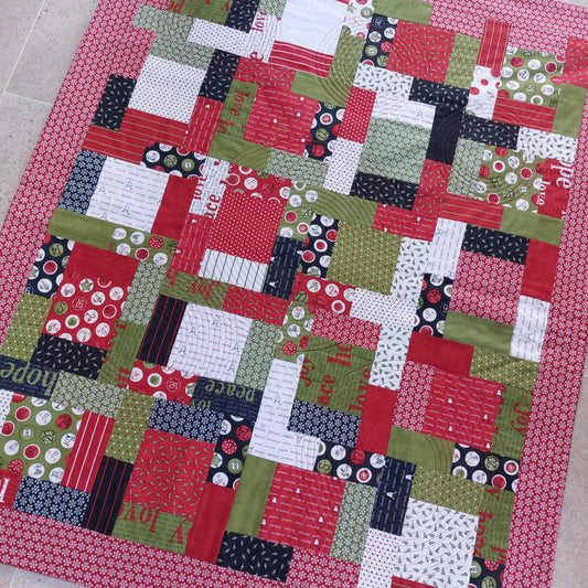 Patchwork quilt with a variety of colourful fabric squares on a tiled floor.