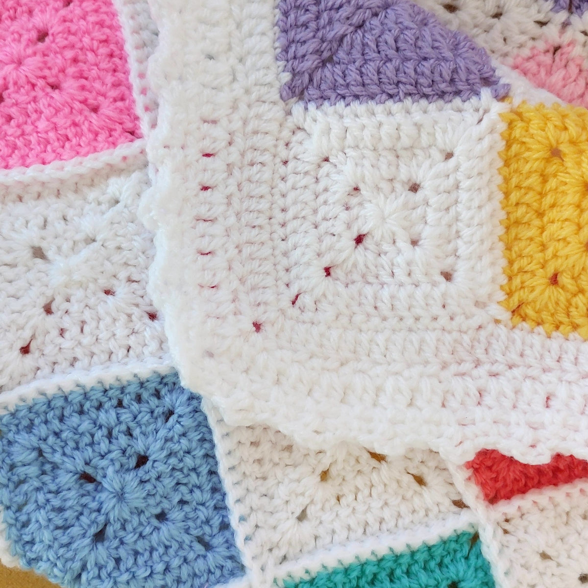 Close-up of a colorful crocheted blanket with various square patterns.
