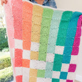 handmade crochet rainbow baby blanket being held up to see the flower squares