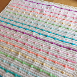 the handmade crochet rainbow bobble blanket on a table