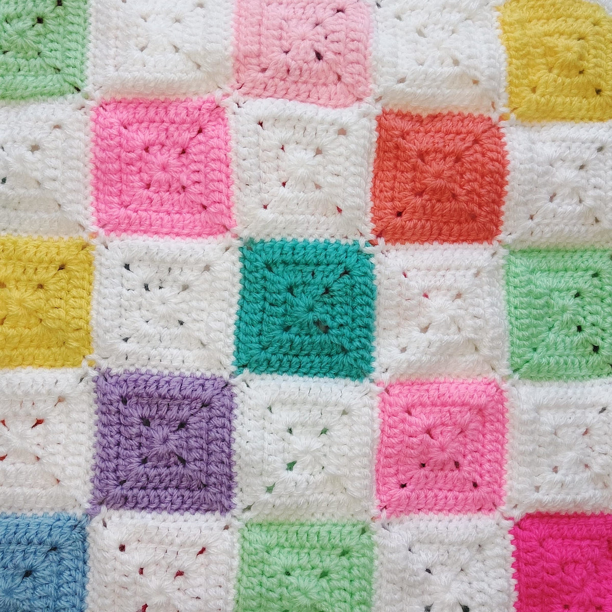 Colorful crocheted blanket with square patterns in various pastel colors.