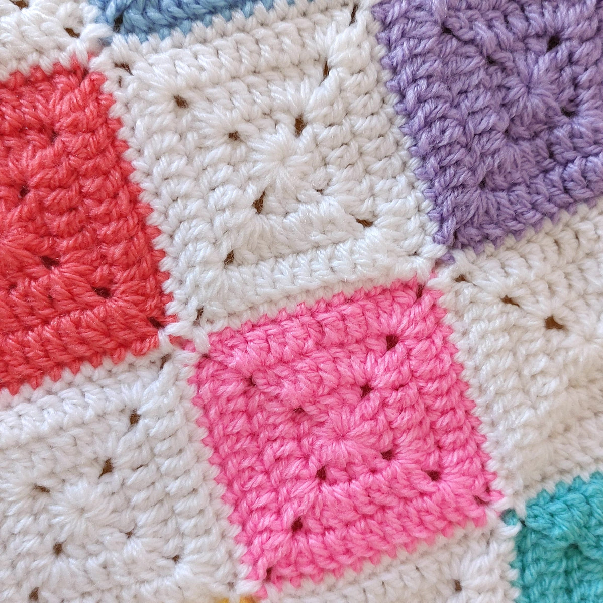 Close-up of a colorful crochet blanket with square patterns.