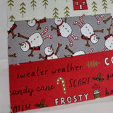 Fabric with snowman pattern and Christmas-themed text on a red background