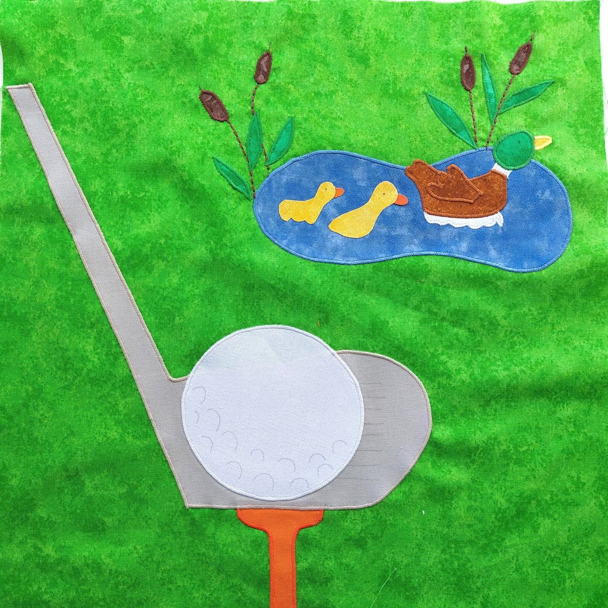 a golf ball on a golf tee with a pond with ducks on it in the background