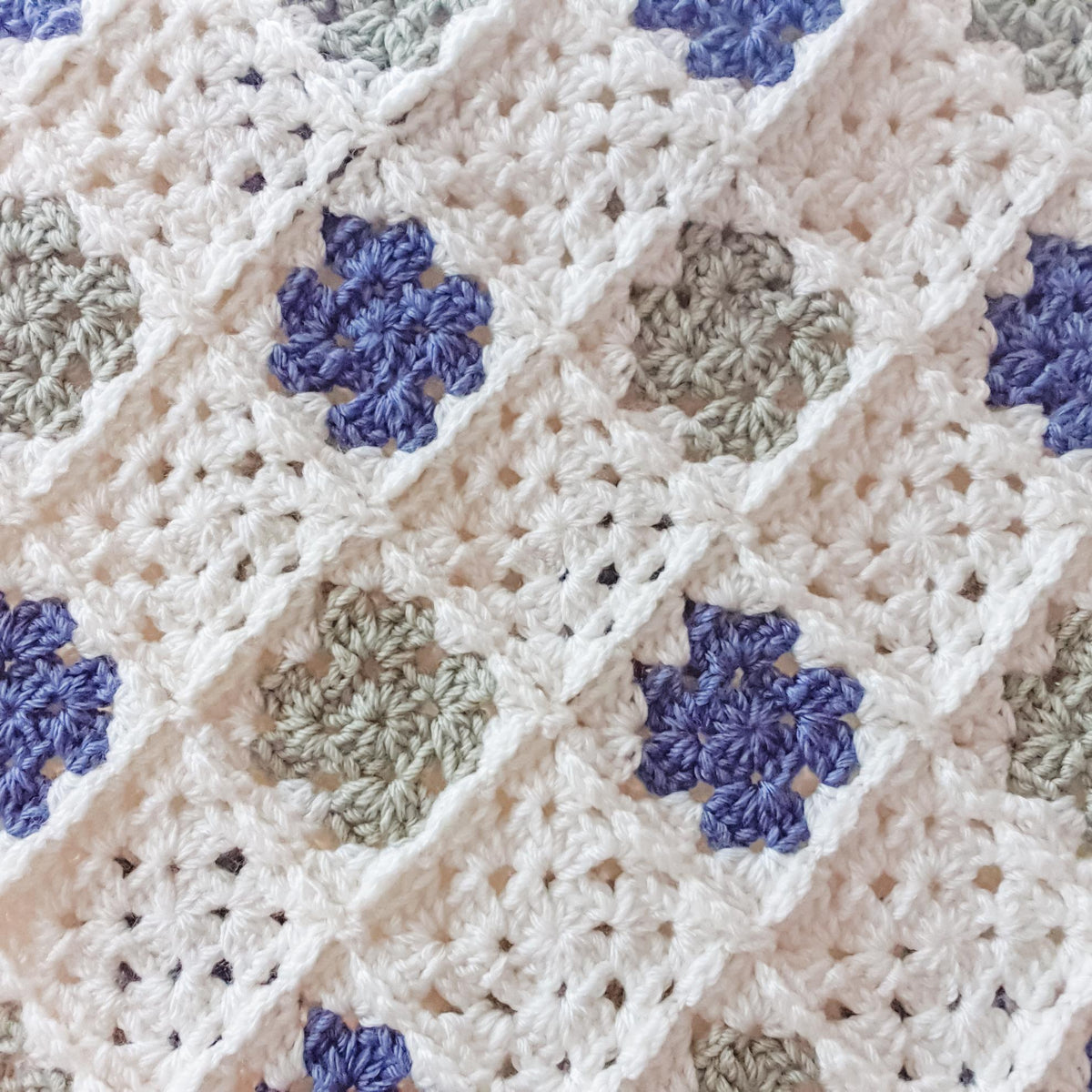 close up of crochet squares in this baby blanket in cream, green and blue