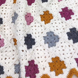 small crochet granny squares of pinks, greys and yellow alternating with cream