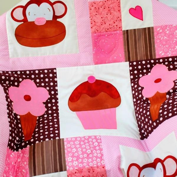 pink, white and brown patchwork squares with a smiling monkey, 2 ice creams and a large cupcake