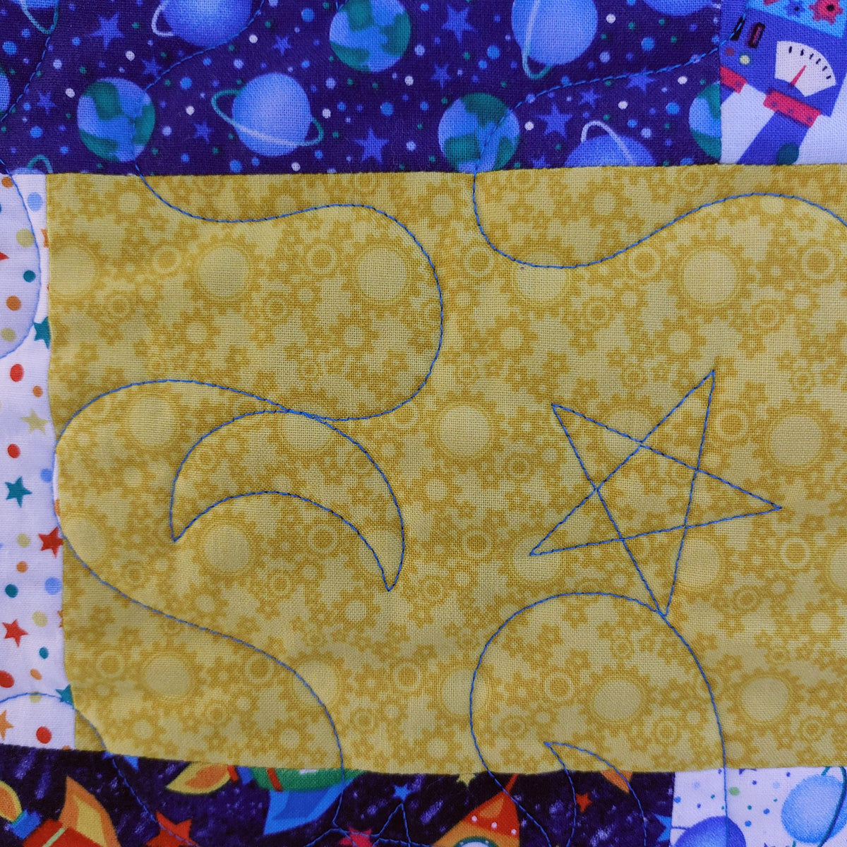 Quilt block with yellow fabric featuring star and moon shapes on a colorful background.