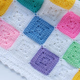 Colorful crocheted blanket with square patterns on a white background