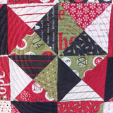 Quilt with geometric pattern featuring triangles and text in red, green, and black.