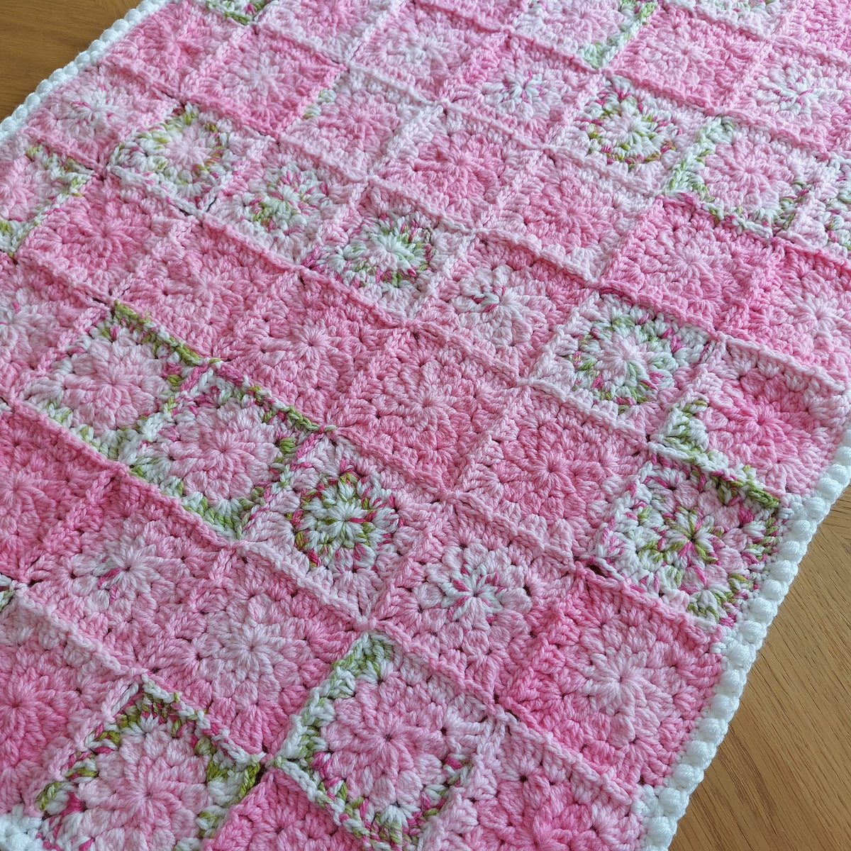 pink and green crochet flower squares joined together to make a blanket