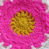 close-up of a crochet pink flower with a yellow centre