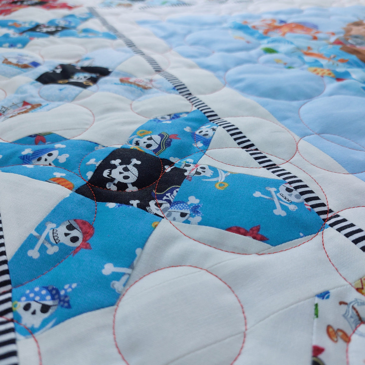 Close-up of a bubble quilting with pirate-themed fabric pieces on a blue background