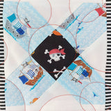 Quilt block with pirate design featuring a skull and crossbones on a blue background.