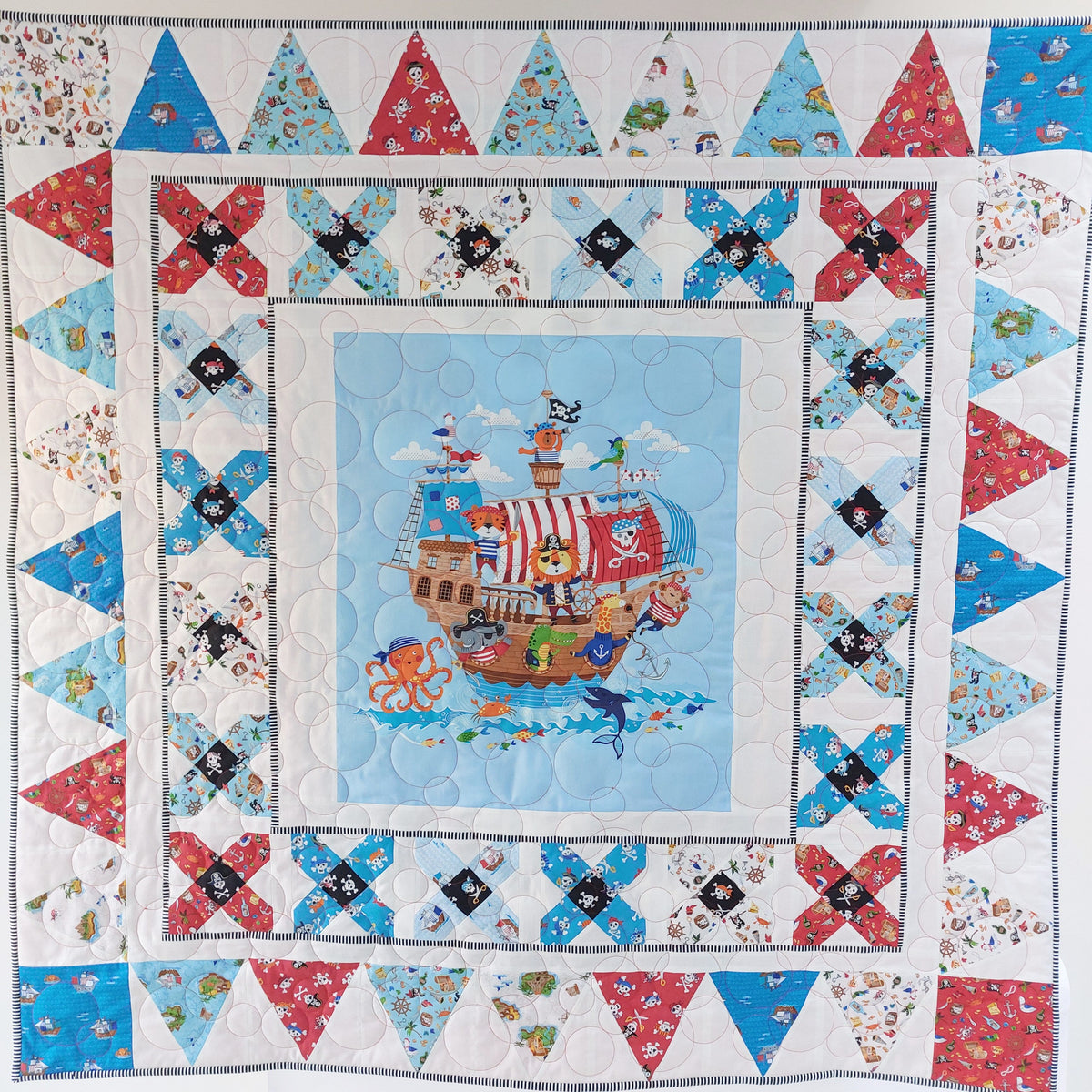 Children's quilt with pirate ship design and colorful triangle patterns