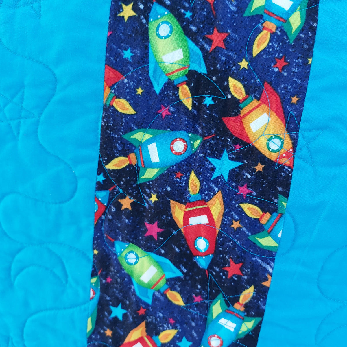 a close up of the back of the rockets and robots quilt showing brightly coloured rockets and bright stars