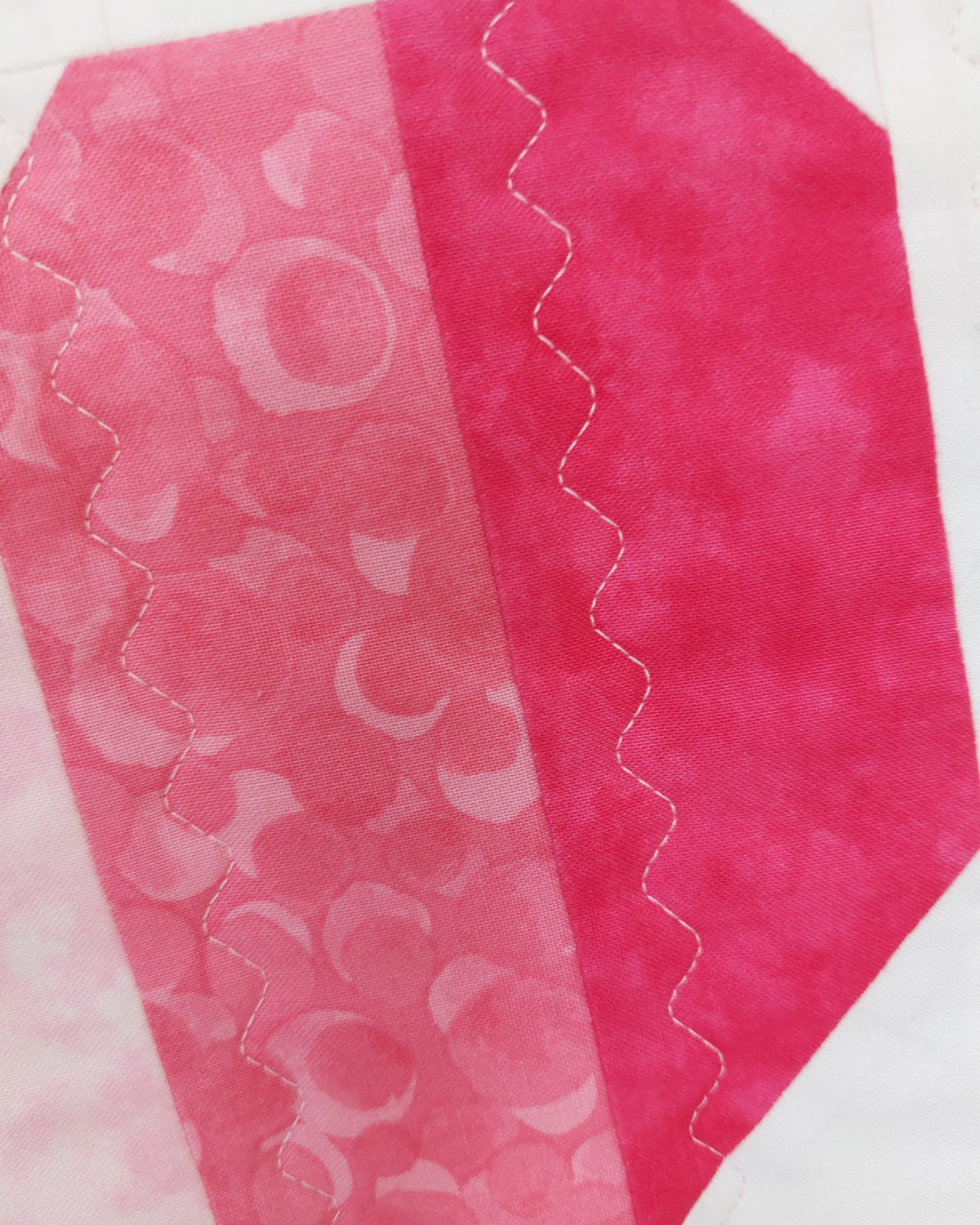 half of a heart showing strips of pink and bright pink fabric