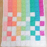 rainbow coloured flower squares on the baby blanket in colours of peach, pink, orange, yellow, green, aqua and purple.