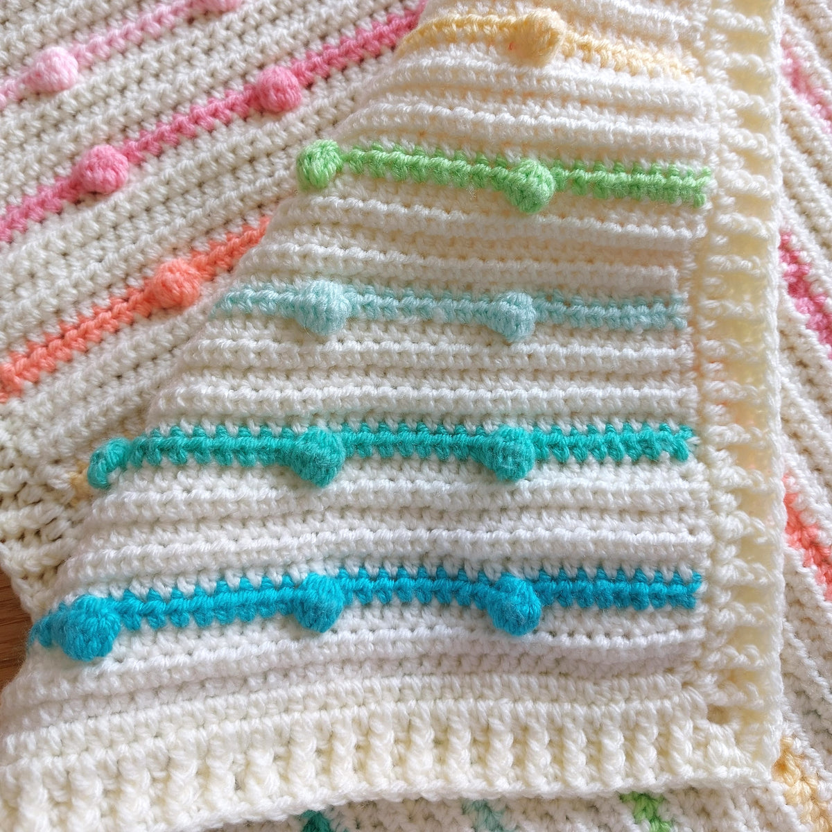 the handmade crochet rainbow bobble blanket folded over to show the different rainbow colours