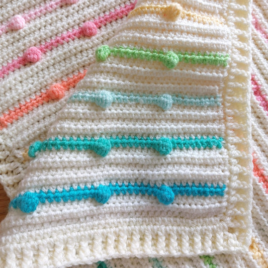the handmade crochet rainbow bobble blanket folded over to show the different rainbow colours