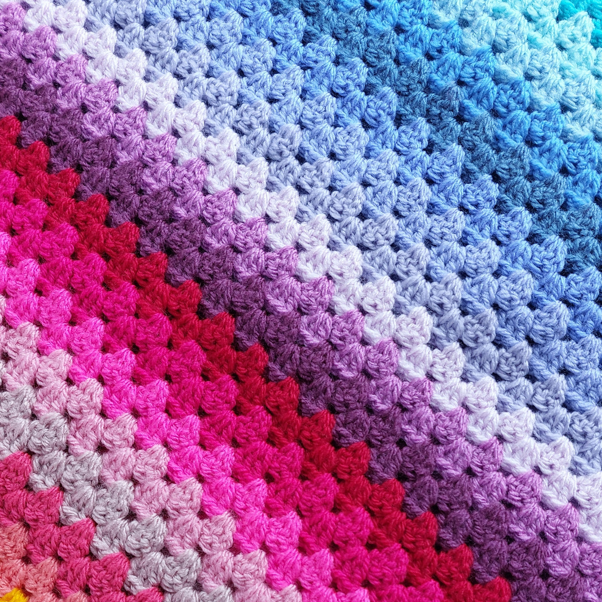 Colorful crocheted blanket with a gradient of pink, purple, blue, and red.