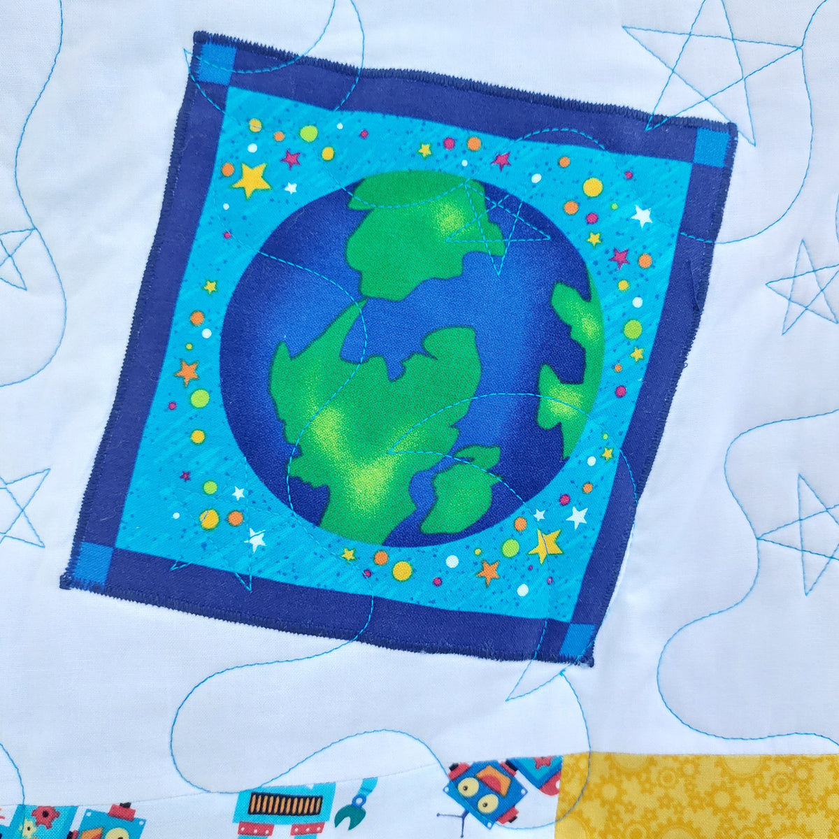 Fabric square with a colorful depiction of the Earth on a blue background, surrounded by stars and space-themed elements.