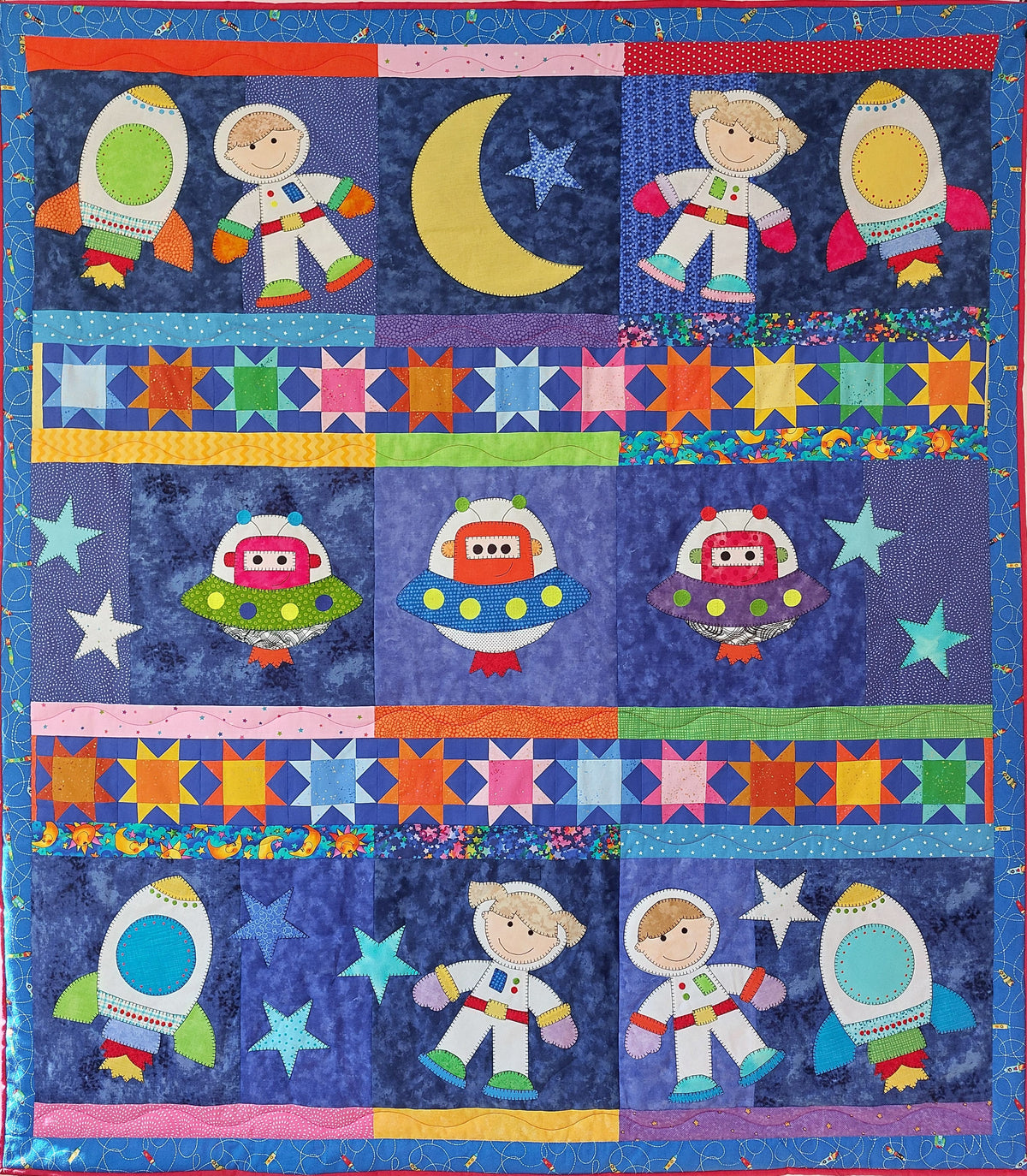 an outer space quilt of different coloured blue fabrics with space girls and boys floating in space with rockets, aliens spaceships and stars