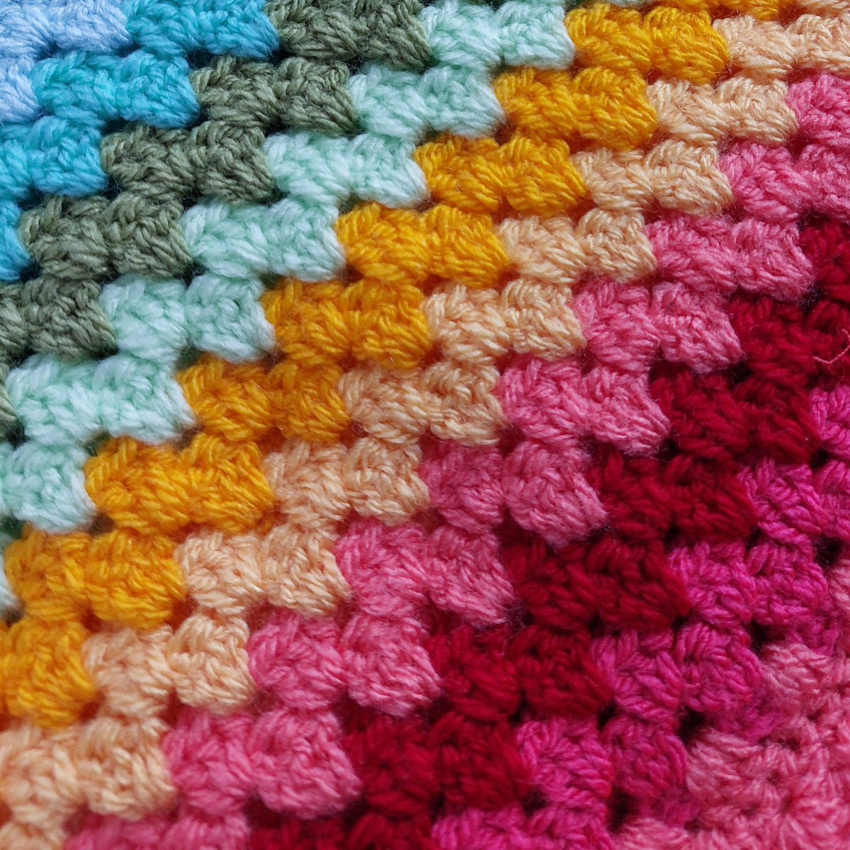 Close-up of a colorful crocheted fabric with a pattern of squares in various colors.