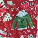 Fabric with Christmas-themed pattern featuring green sweaters, scarves, and snowflakes on a red background.