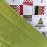 Quilt with Christmas-themed fabric pieces featuring trees with a green backing.