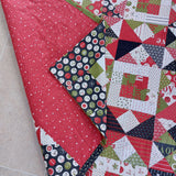 Quilt with red, green, and multicolor patterns on a beige surface