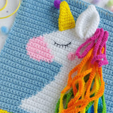 Colorful crochet unicorn on a blue textured background