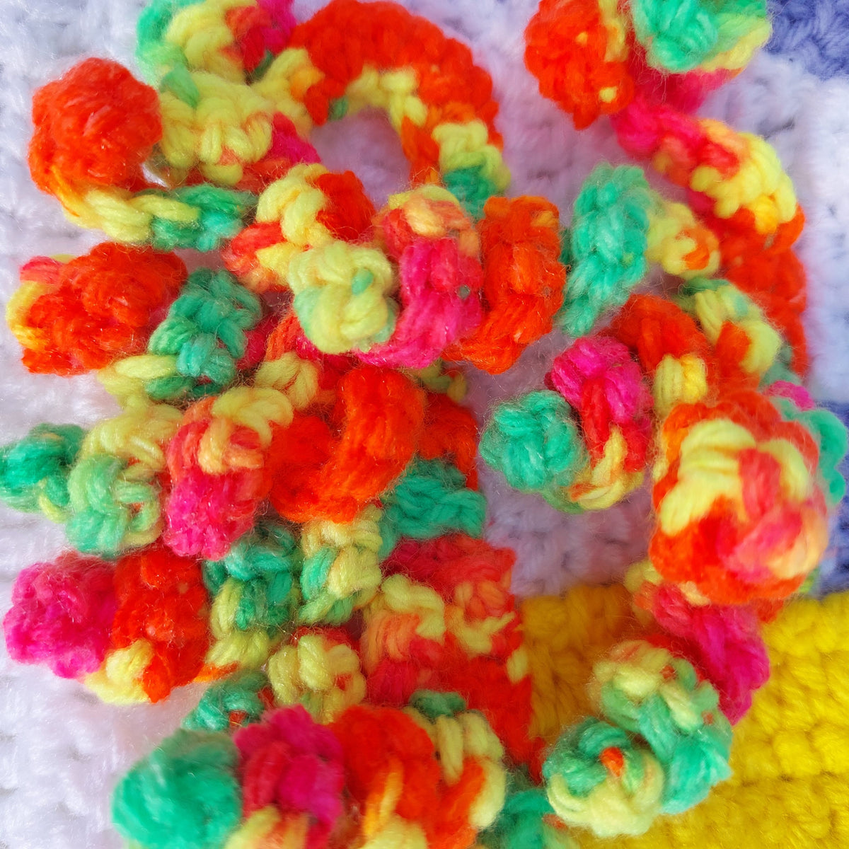 a close up of the brightly coloured unicorn mane on the handmade crochet unicorn blanket