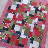 Patchwork quilt with a variety of colorful fabric squares on a tiled floor.