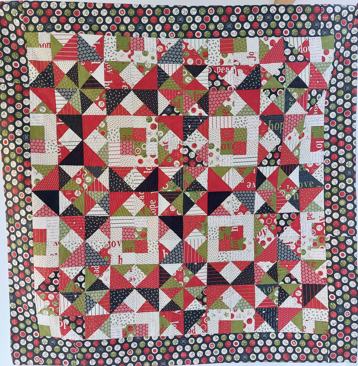 Quilt with geometric pattern featuring red, green, and black colors.