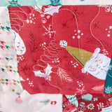 Close-up of Christmas-themed fabric with Santa Claus and holly design on a red background.